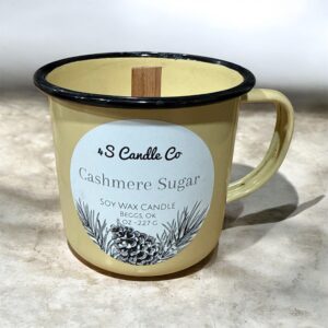 An antique butterscotch yellow camp mug is filled with white wax and a wood wick is centered. The 4S Candle Co winter label with pinecones and leaves are on the bottom of label and candle information is printed above this grapghic with candle weight, product name, location made, scent name and company name.