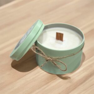 mint green tin candle with wood wick and string with bow attached around the tin. Sitting on a wood table top.
