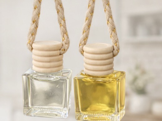 Two car oil diffusers filled with liquid. The diffusers are clear and have a light wood cap and a tan string.