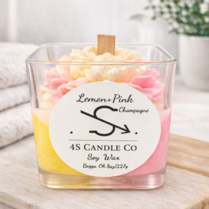 candle in a square clear vessel, tricolor candle with pink, red, and yellow wax in a triagnle stacked design, wood wick, flower embeds. Front has the 4S Candle Co logo labeled with the name Lemon + Pink Champagne. Label has soy wax, Begs, Ok and 8oz/227g printed.