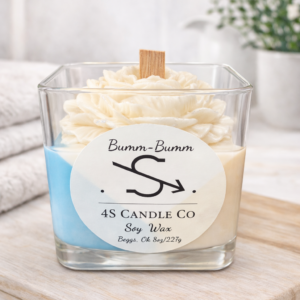 Candle in a square clear vessel, tricolor candle with tan, blue, and white wax in a triangle stacked design, wood wick, flower embeds. Front has the 4S Candle Co logo labeled with the name Bumm-Bumm. Label has soy wax, Begs, Ok and 8oz/227g printed.