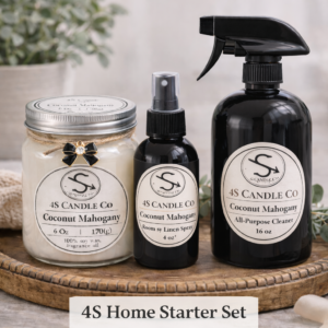 The 4S Home Starter Set is labeld on this photo and features a 6oz mason jar candle with a 4oz room spray bottle, and a black 16 oz all purpose cleaner spray bottle. Each container has a 4S Candle Co label with product information. All three products are setting on a rustic circular wood tray. The background consists of a blanket, and a vase with plants.