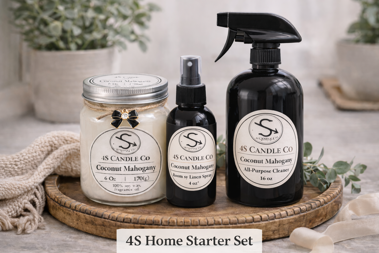 The 4S Home Starter Set is labeld on this photo and features a 6oz mason jar candle with a 4oz room spray bottle, and a black 16 oz all purpose cleaner spray bottle. Each container has a 4S Candle Co label with product information. All three products are setting on a rustic circular wood tray. The background consists of a blanket, and a vase with plants.